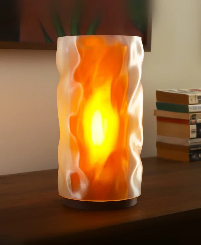 Lampe NAMI allumée, aux lignes ondulées, sur une console en bois
